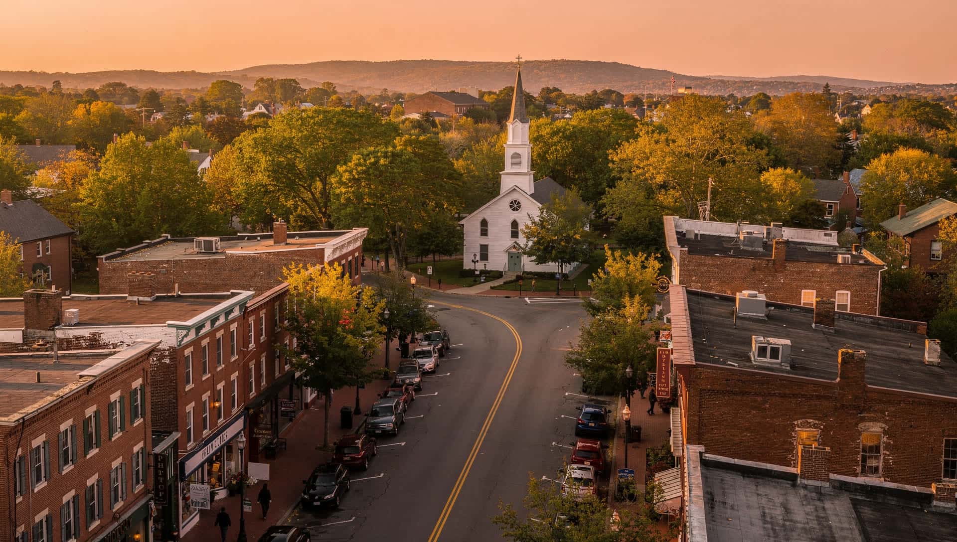 An aerial view of a New England town center with local storefronts at dusk