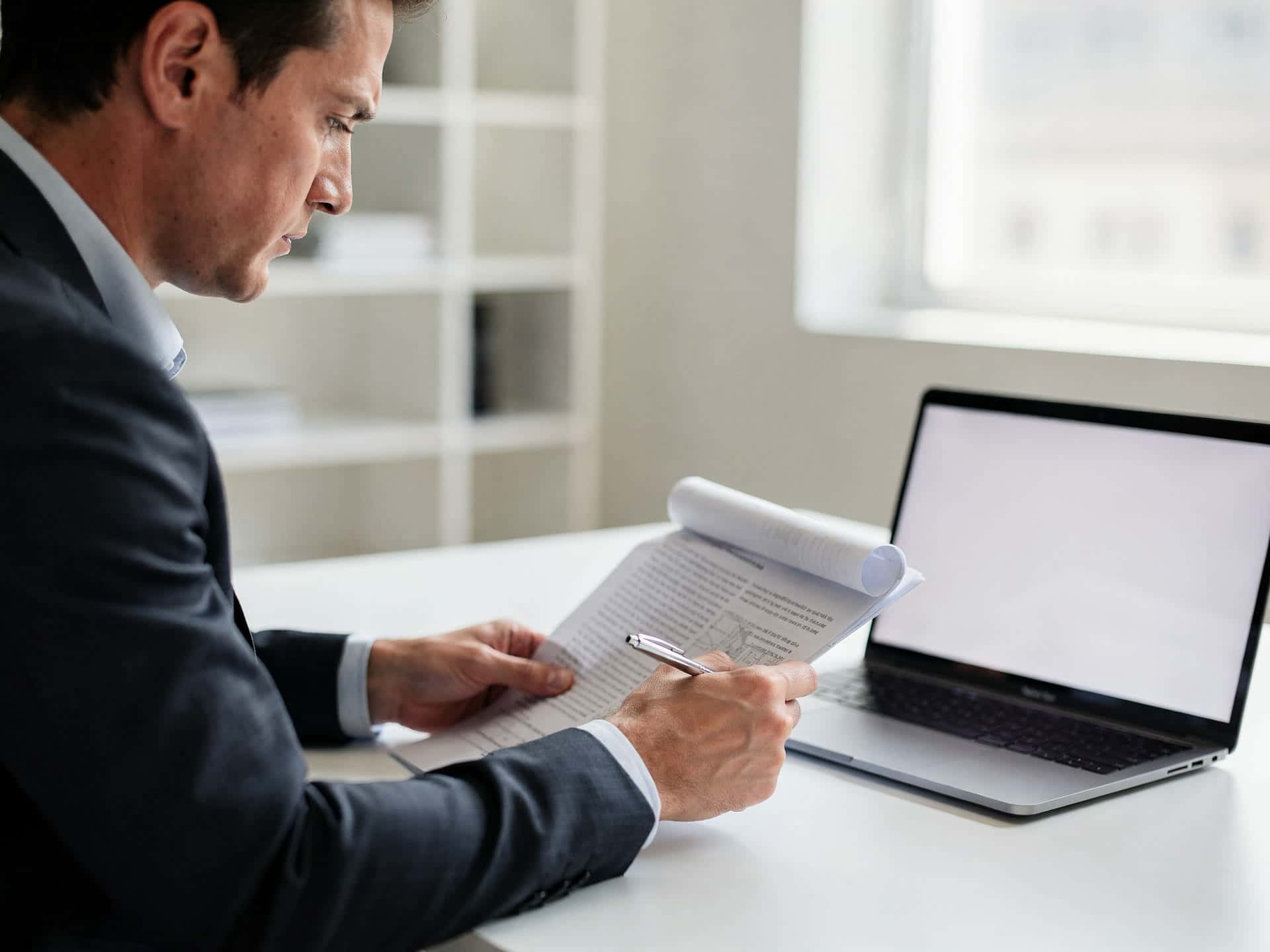 A consultant reviewing a processing statement line by line at a laptop